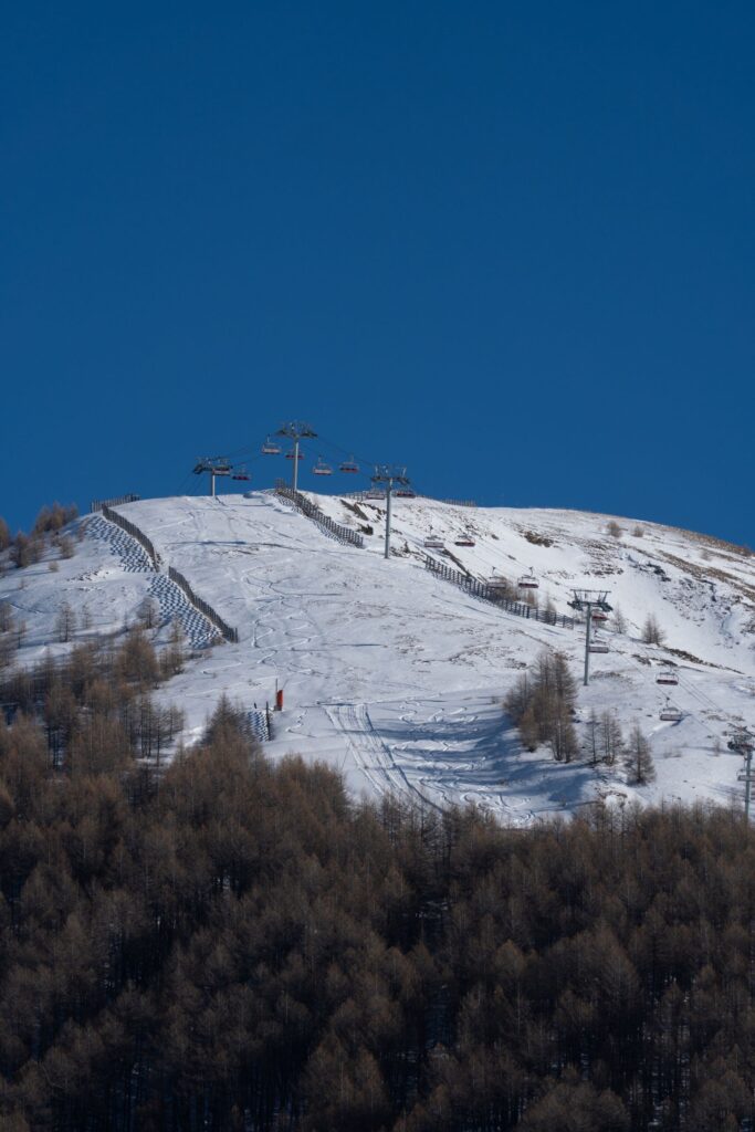Chairlift line climbing a snow-covered ski slope under a deep blue sky