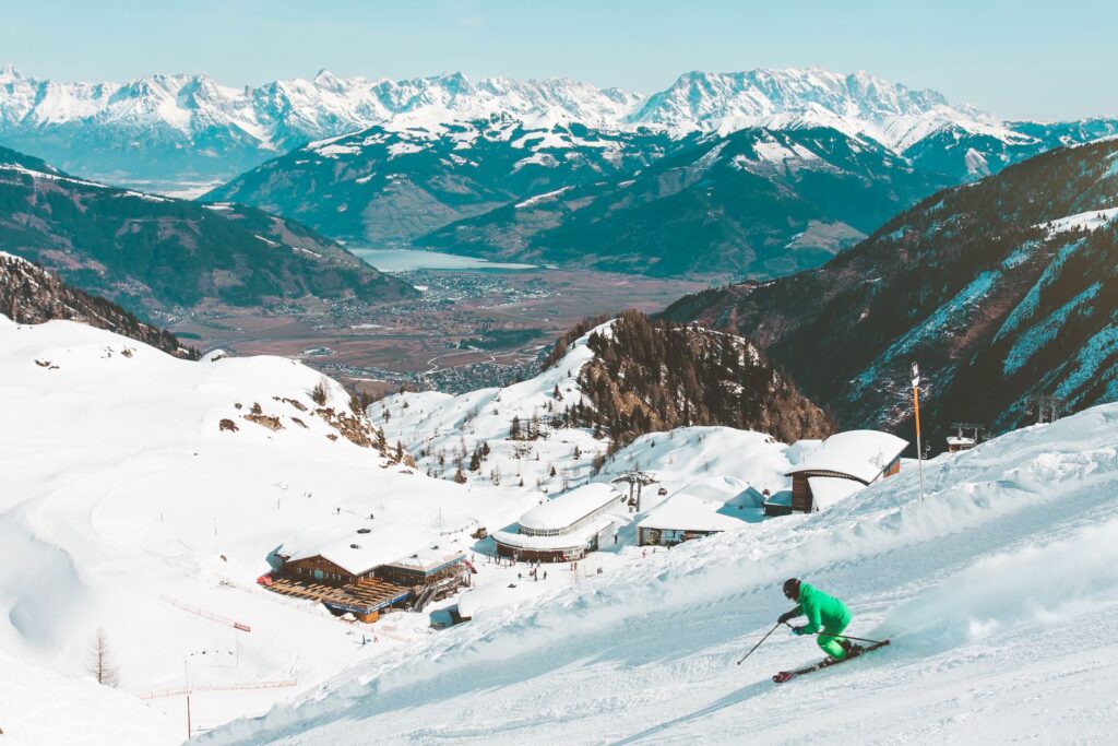Skier on a sunny piste with a wide Alpine panorama behind