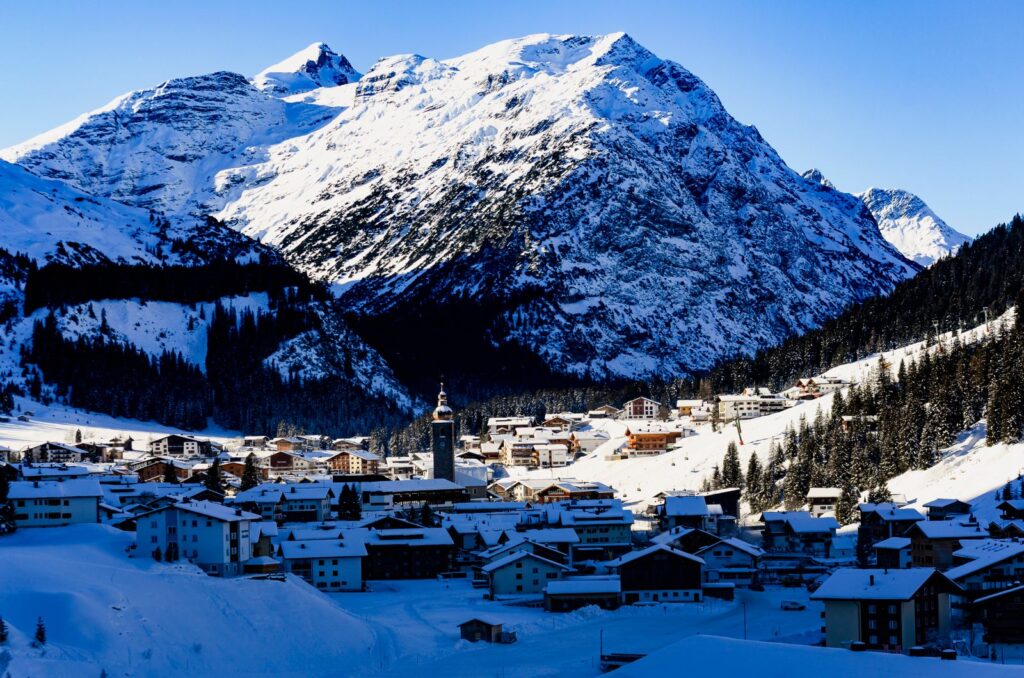 Snow-covered Alpine village of chalets and hotels below a large snowy mountain